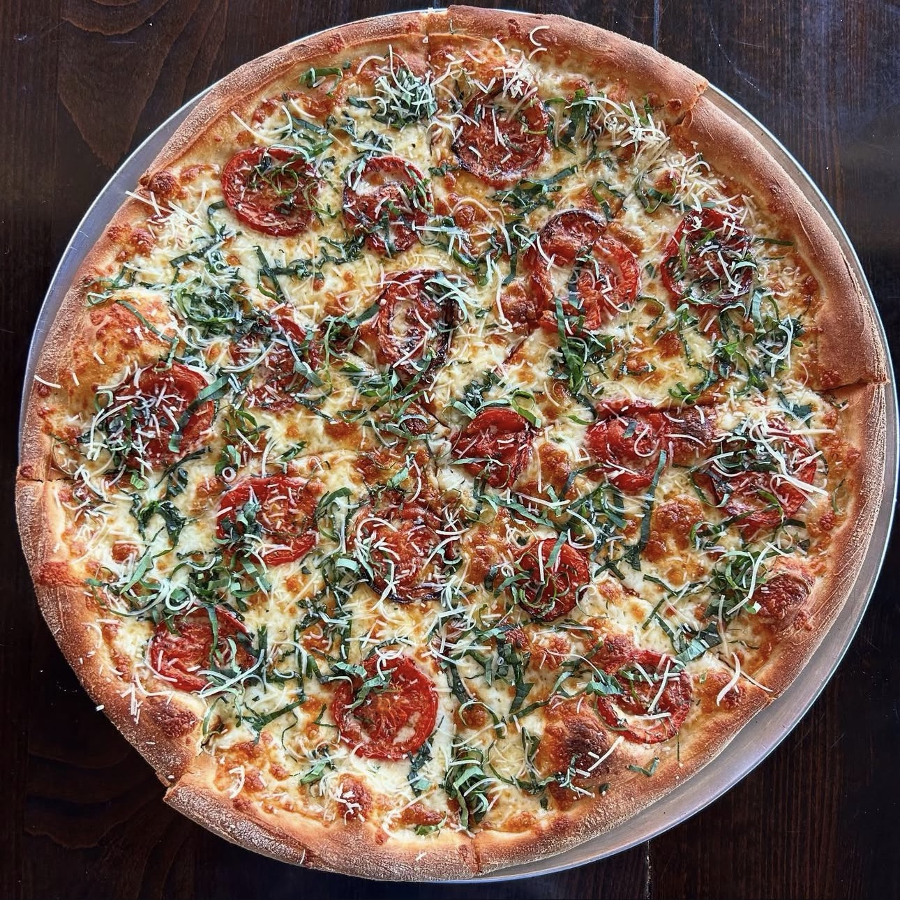 Tomato and basil pizza finished with grated cheese.